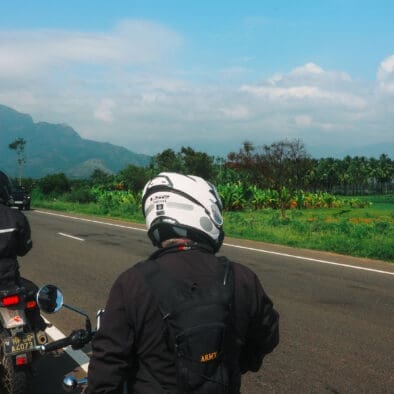 Motorcyclists on a scenic road in Kerala with mountains in the background.
